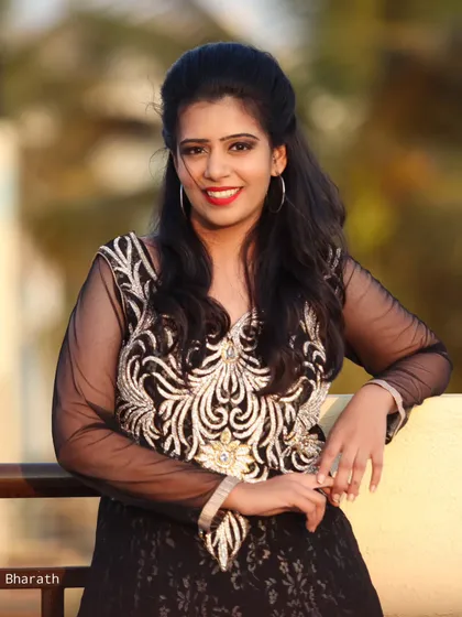 A classic portrait of the model in the black gown, leaning against a balcony with a warm, soft background.