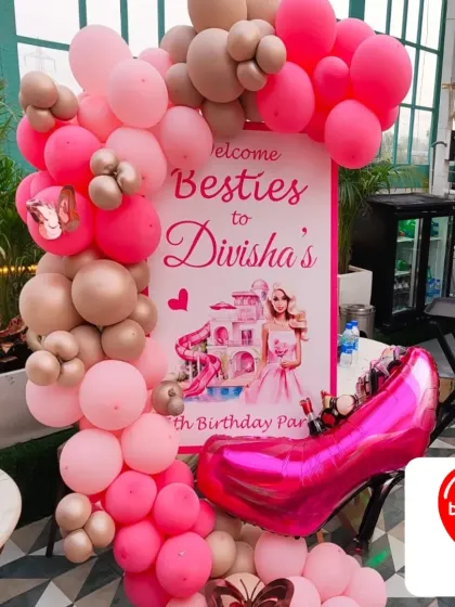 A welcome stand for a Barbie-themed birthday party. It features a custom "Welcome Besties" sign, a pink high-heel foil balloon, and a pink and gold balloon garland.