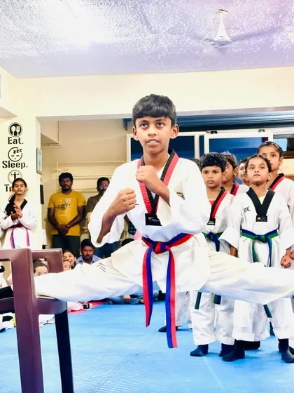This student shows incredible flexibility and strength, performing a split between two chairs as part of his belt test demonstration.