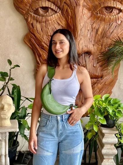 A customer looking radiant with her Selena Studded bag in Jade green. It’s a perfect pop of color against a simple, classic outfit of a white tank and jeans.