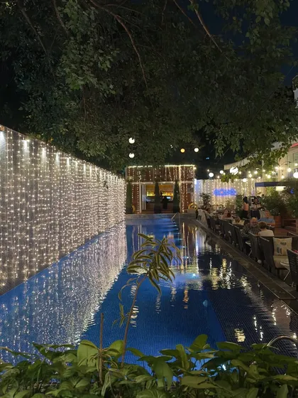 Aqua by night, decorated with festive fairy lights for Deepawali. The reflection on the pool surface creates a magical, shimmering atmosphere for our guests.