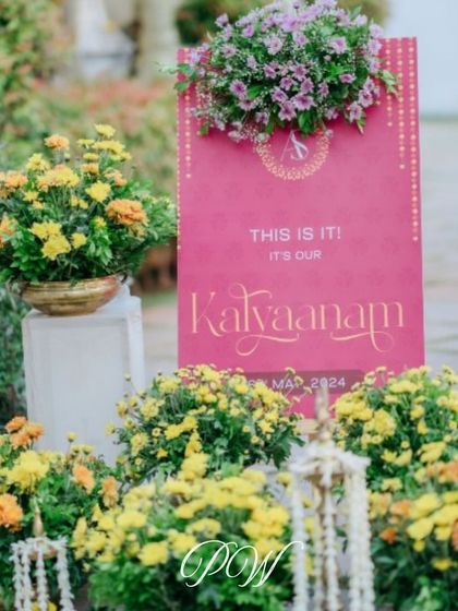 "This is it! It's our Kalyaanam." A beautiful and modern welcome sign, surrounded by vibrant marigolds, setting the perfect tone for a South Indian wedding.