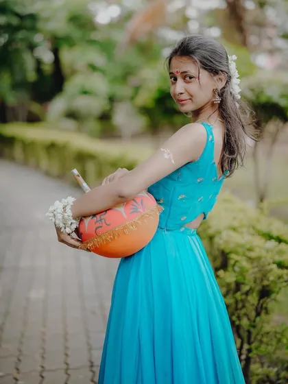 A playful and devotional portrait, with the model holding a matka (clay pot), reminiscent of Radha's stories.