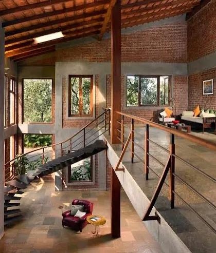 A view from the mezzanine bridge in The Mango House. This perspective showcases the home's layered design, with its mix of exposed brick, raw concrete, and warm wood, all under a sloping roof with terracotta tiles.
