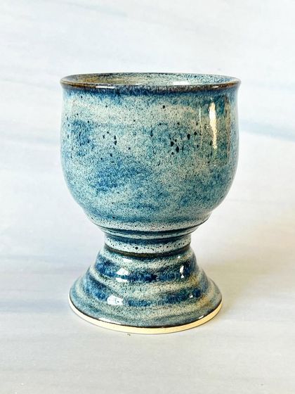 This wheel-thrown ceramic goblet has a classic shape, perfect for wine or water. The stormy blue glaze is full of movement and texture.