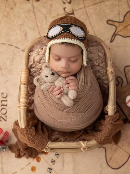 This little traveler is dreaming of all the places he'll go. The combination of the soft swaddle, teddy bear, and adventure props makes for a truly imaginative newborn portrait.
