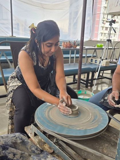 Here you can see a guest getting comfortable with the pottery wheel, focusing on shaping her first creation. It's a rewarding process of patience and creativity.