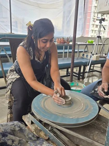 A participant gets focused as she works the clay on the wheel, with her partner looking on. It's a great activity to do side-by-side, sharing the experience.