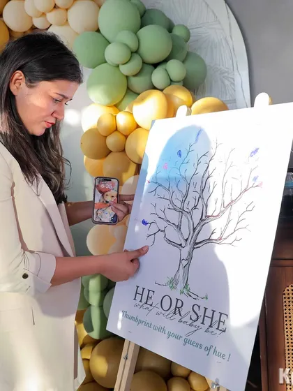 A guest carefully adds her thumbprint to the gender reveal tree, a beautiful and interactive piece of decor.