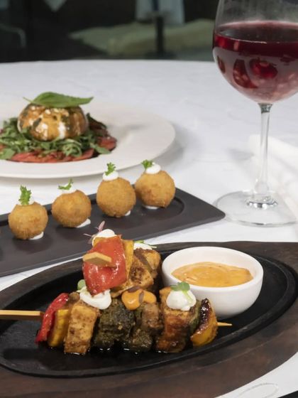 A spread of our popular tapas, including vegetable skewers and croquettes, paired with a glass of red wine. This is the perfect start to a Spanish feast.