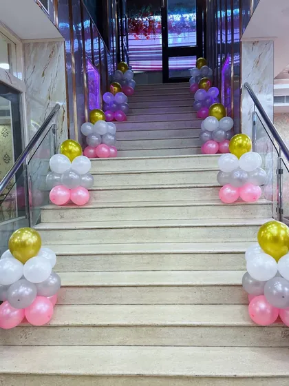 Staircase decoration with pink, white, and gold balloon clusters for a party entrance.