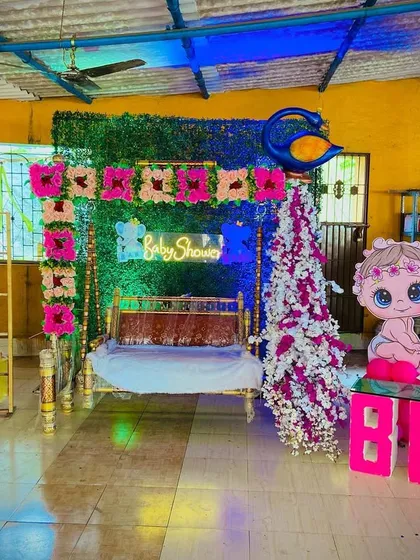 A full view of the baby shower stage with a traditional swing, peacock prop, and 'Boy' or 'Girl' themed decorations.