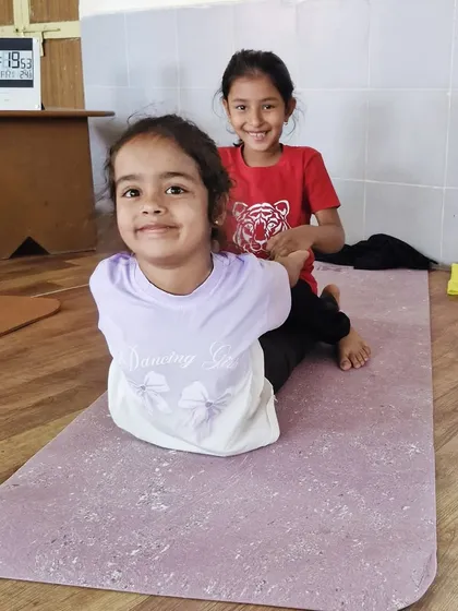 A younger participant gets some help in a gentle backbend. My classes are adapted for all age groups, ensuring every child feels included and supported.
