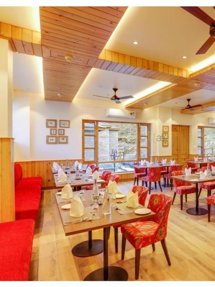 Another view of the dining area, with comfortable red banquette seating and wood-paneled columns that create a cozy, rustic atmosphere.