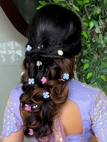 A whimsical and romantic bubble braid, adorned with colorful flowers. This hairstyle is perfect for a fun-loving bride at her Mehendi or Haldi function.
