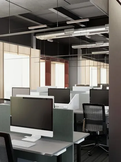 The open-plan workstation area in a modern office, designed for collaboration and focus. The layout maximizes natural light from the large windows, with exposed ceiling ducts adding an industrial touch.