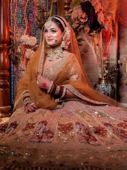 A full seated portrait of the bride, her magnificent lehenga spread around her in a regal pose.