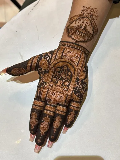 This design features a 'jharokha' (ornate window) with peacocks, giving it a very royal and architectural feel. The fingers are adorned with matching intricate patterns.