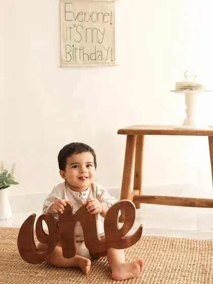 It's all about the "one." This playful shot with the large wooden "one" prop is a fun way to highlight the big milestone. The baby's happy expression says it all.