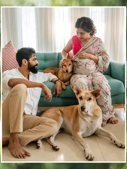 A picture-perfect family portrait. This shot captures the couple with their two Indie dogs, relaxed and happy in their home, framed by a soft, natural border.