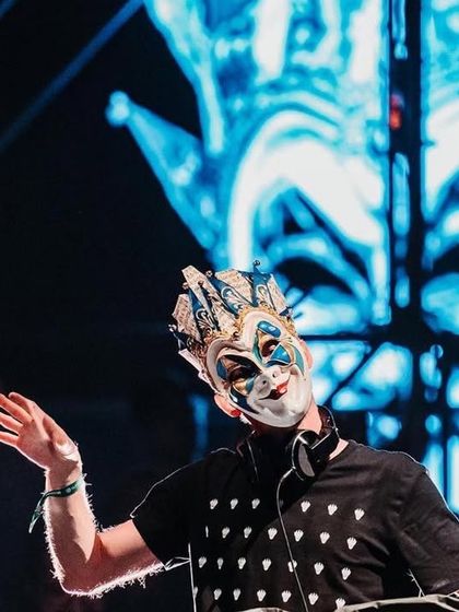 A close-up of Boris Brejcha in his element, with a massive visual of his mask projected behind him.