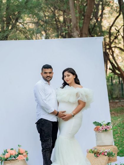 This couple's portrait showcases their connection and shared excitement. The outdoor setting with a clean backdrop keeps the focus entirely on them and their journey to parenthood.