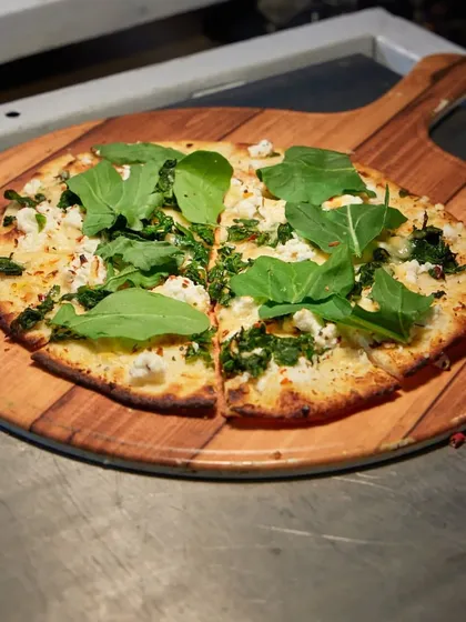 Another view of our popular Greens and Cheese pizza, showcasing the fresh arugula and generous toppings on a perfectly crisp crust, served straight from the oven.
