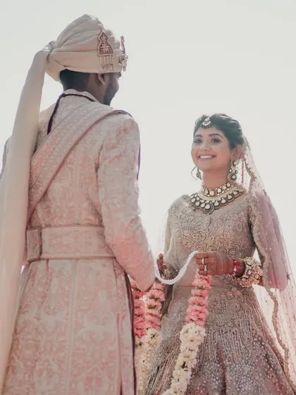 The bride's radiant smile as she exchanges garlands with her groom. We focus on creating a perfect setting for these timeless wedding photographs.