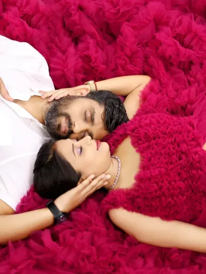An artistic top-down shot of a couple lying on the ruffles of a magenta gown. This creative pose highlights their connection and the beautiful texture of the dress.