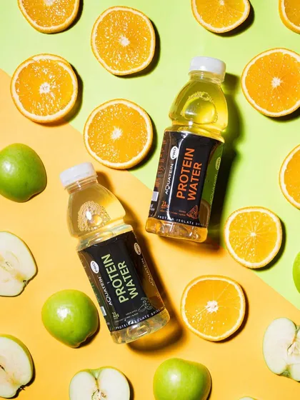 A vibrant and colorful flat lay of protein water with fresh fruits. The composition is energetic and healthy, perfectly matching the product's branding and appeal.