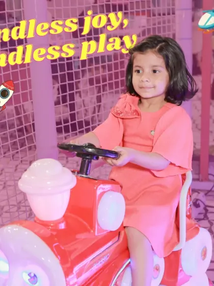 Endless joy, endless play. A little girl enjoys a ride on a bright red toy train, one of the many fun rides available for our youngest visitors.