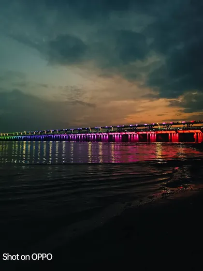 A dusk shot over a river, using the AI mode of the Oppo Reno 8 Pro. The camera's technology enhances the colors of the bridge and sunset, creating a vivid and colorful nightscape.