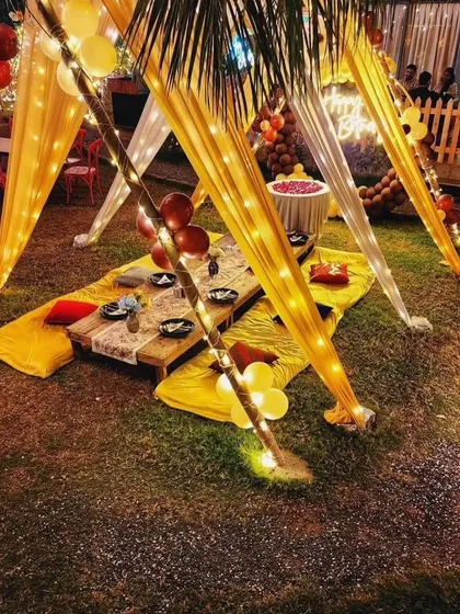 A view of the low-seating arrangement under the decorated gazebo, with cushions and a rustic table set for guests.