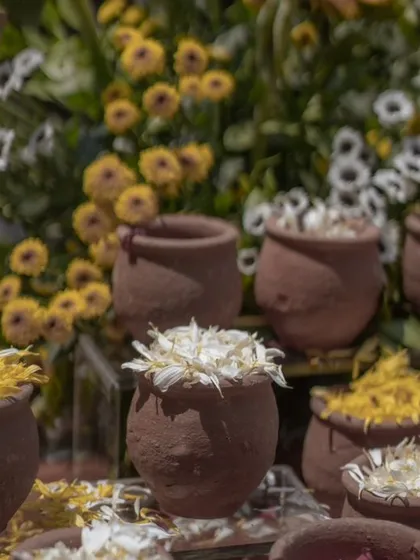A close-up of terracotta pots filled with flower petals, part of a beautiful and traditional Haldi setup.