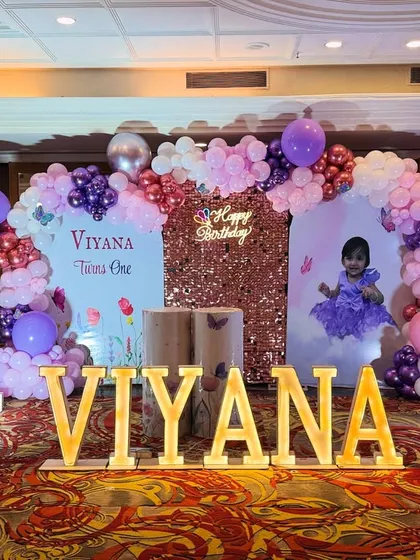 A wider shot of Viyana's party decor, showing the light-up number '1', 'BABY' blocks, and butterfly-topped balloon columns that complete the look.
