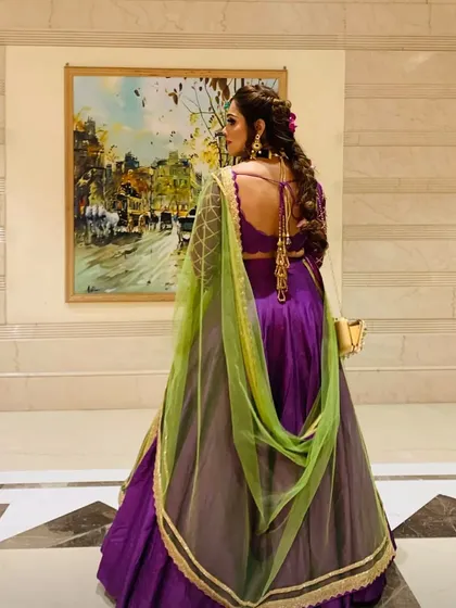 The back of an outfit is just as important as the front. This stunning purple lehenga features a deep back and intricate details, paired with a contrasting green chunni for a bold bridesmaid look.