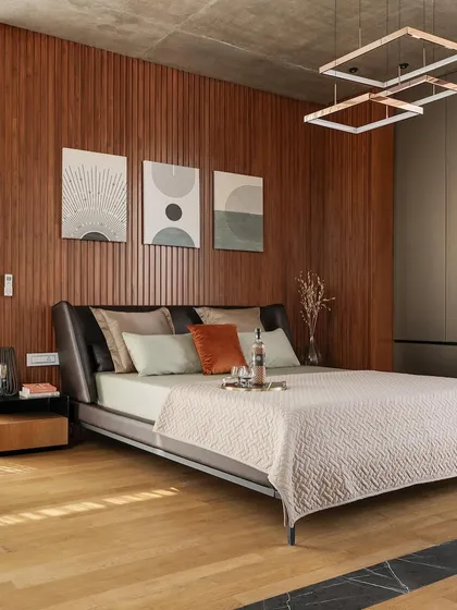 In this bedroom, a feature wall of fluted wood paneling adds texture and warmth. The design is minimalist yet comfortable, creating a serene personal space for rest and relaxation.