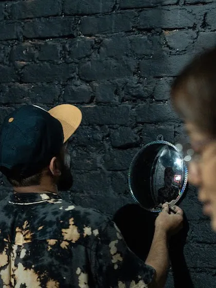 A candid moment during the setup of the 'Surfing' installation, inspecting one of the convex mirrors before it's mounted on the wall.