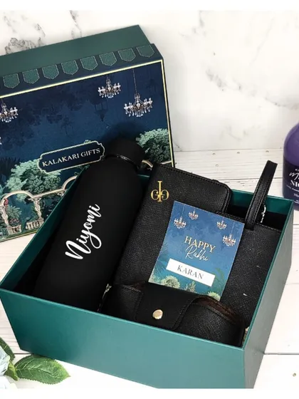 A sleek and stylish Rakhi hamper for him in all black. It features a personalized water bottle, a passport cover, and an eyewear case, all packed in a luxurious gift box.