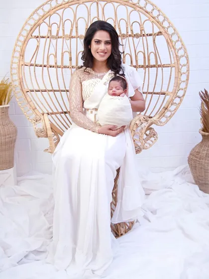 This white frill saree is a unique piece for a newborn photoshoot. It comes with a designer blouse and features delicate Aari embroidery of a mother and baby on the pallu, adding a personal and sentimental touch to your photos.