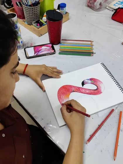 A series of images showing an adult student drawing a vibrant flamingo with color pencils, from the initial sketch to the final blended colors.