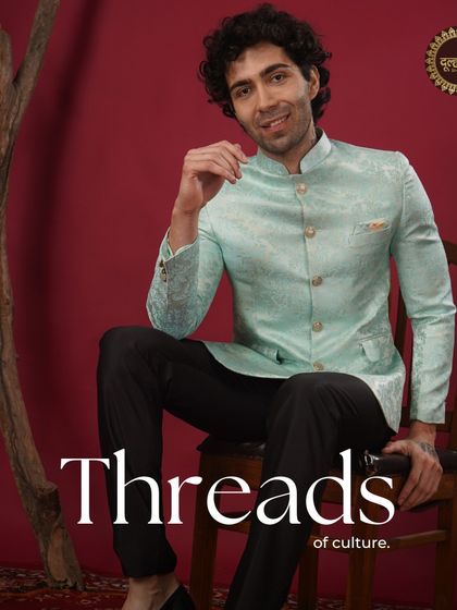 Threads of culture. A model sits confidently in a pastel blue brocade Bandhgala, a perfect blend of modern style and traditional fabric.