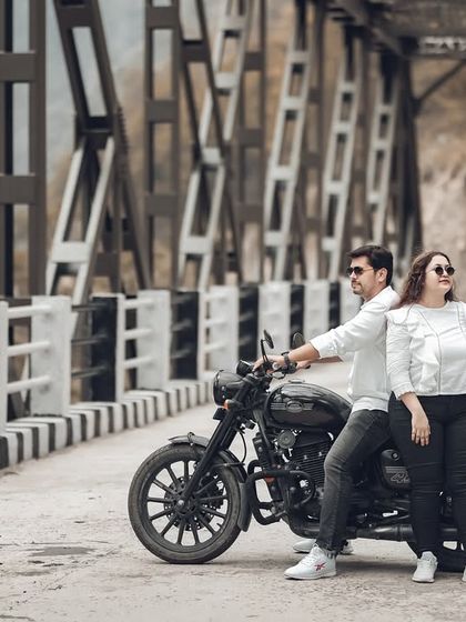 A stylish pose on the bridge, with the couple and their motorcycle. The industrial architecture of the bridge provides a great contrast to the natural mountain scenery.