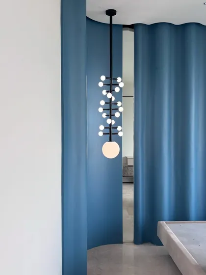 We believe lighting is sculpture. This custom-made, DNA-patterned light fixture was designed as a conversation starter for this bedroom. It’s a statement piece that demonstrates our commitment to creating unique, bespoke elements that define a room's character.