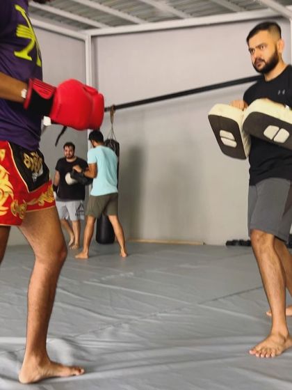 A coach focused on his student during a pad work drill.