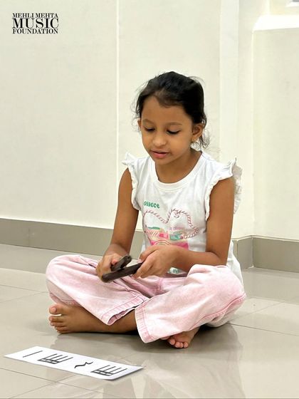 A student carefully studies the notation on her flash card before playing. This exercise develops concentration and the crucial skill of sight-reading.