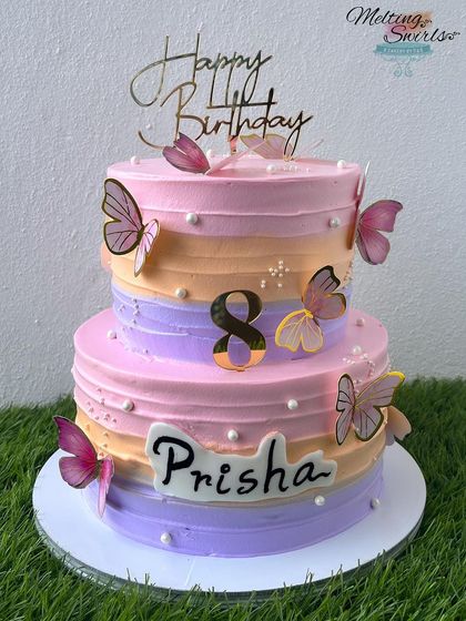 A beautiful two-tier cake in pastel shades, decorated with delicate butterflies for an 8th birthday. The bottom tier is chocolate mousse and the top is lemon raspberry.