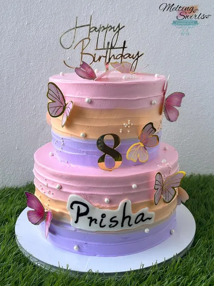 A beautiful two-tier cake in pastel shades, decorated with delicate butterflies for an 8th birthday. The bottom tier is chocolate mousse and the top is lemon raspberry.