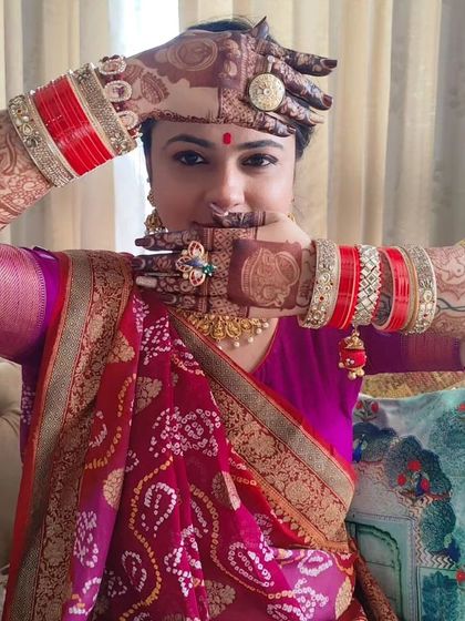 A happy bride showing off her portrait mehendi, complete with her wedding bangles.