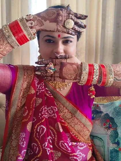A happy bride showing off her portrait mehendi, complete with her wedding bangles.